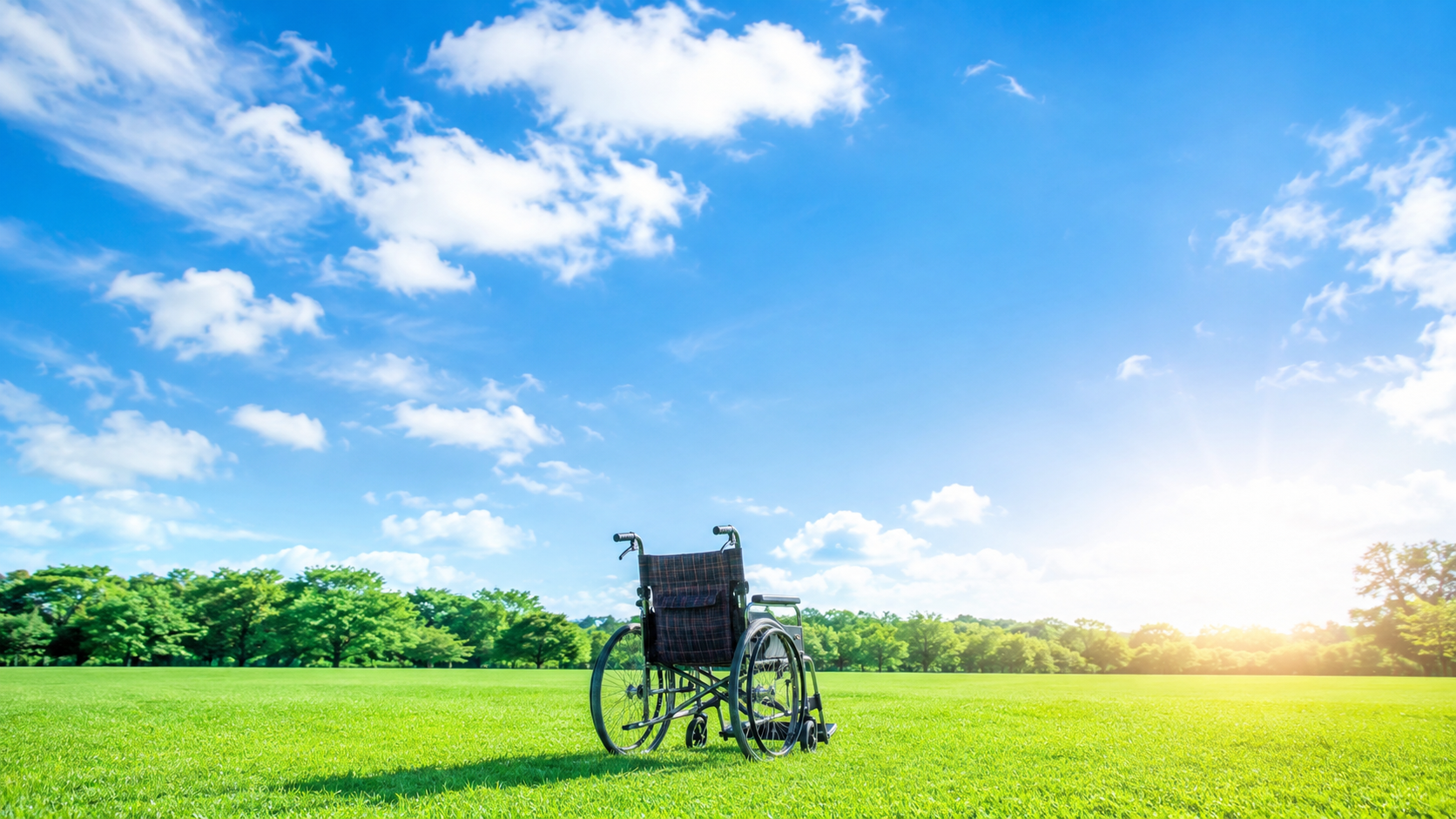 車椅子と青空、緑の芝生の風景